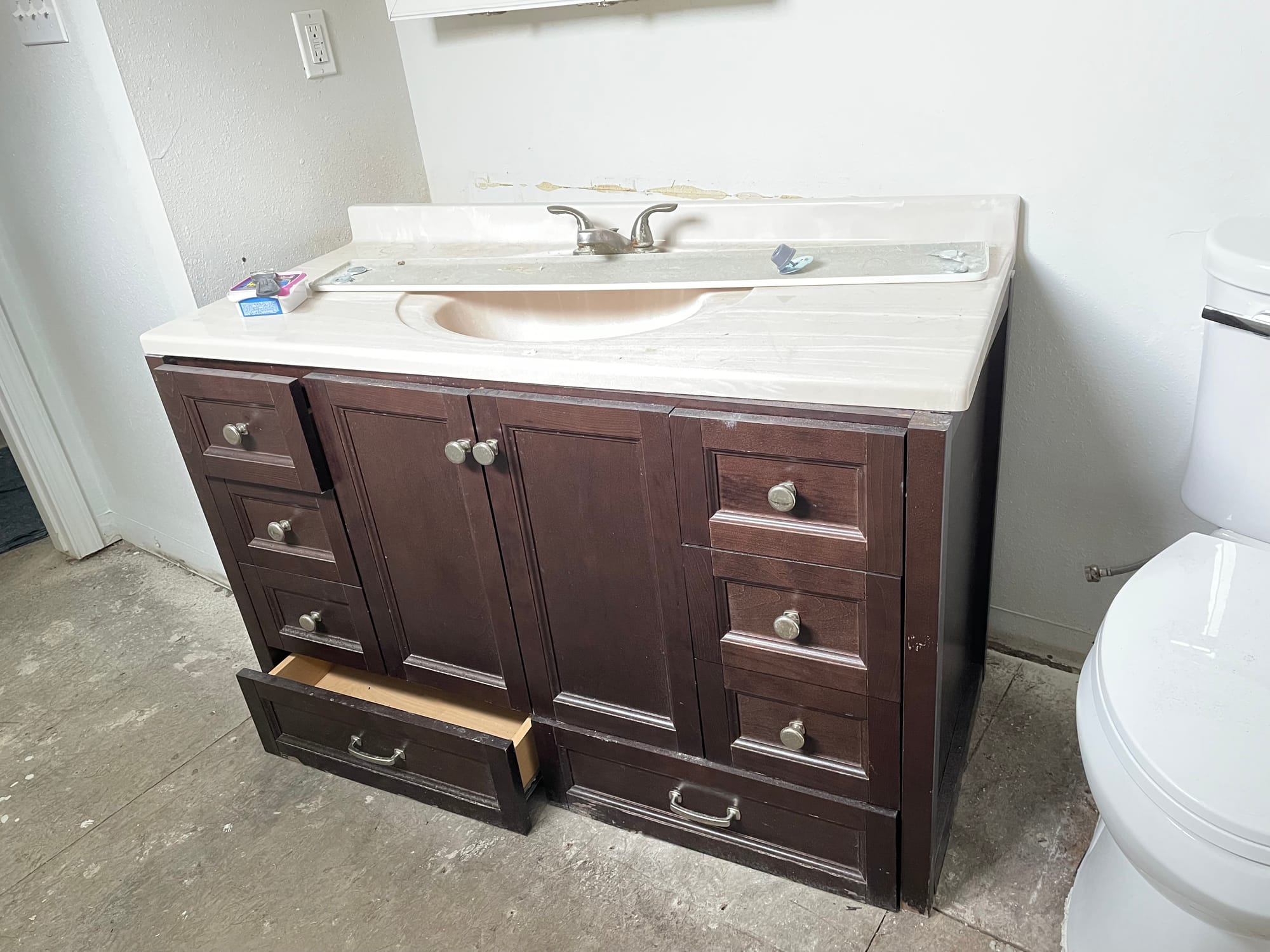 The original vanity: a dark brown cabinet with a cultured marble top and integrated basin.